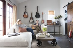male and female on white sectional playing guitar