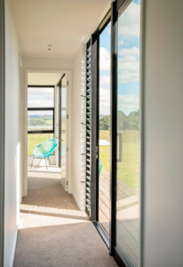Hallway with lots of windows and a modern blue chair at the end