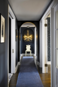 Long hallway with blue runner rug and white chair at the end