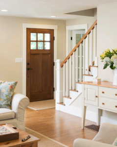 Craftsman style wooden front door with six windows and a white staircase with oak handrail