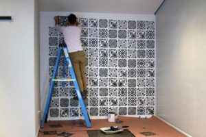 guy on ladder tiling wall