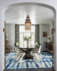 An eclectic dining room uses a tie dye rug to focus the design