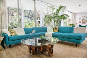 teal sectional behind glass coffee table