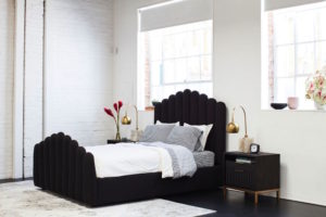 black upholstered bed on left next to black nightstand