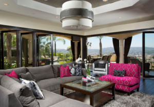 large living room with grey sectional on right and bright pink accent chair on left