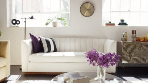 White channeled sofa in middle with yellow chair on left